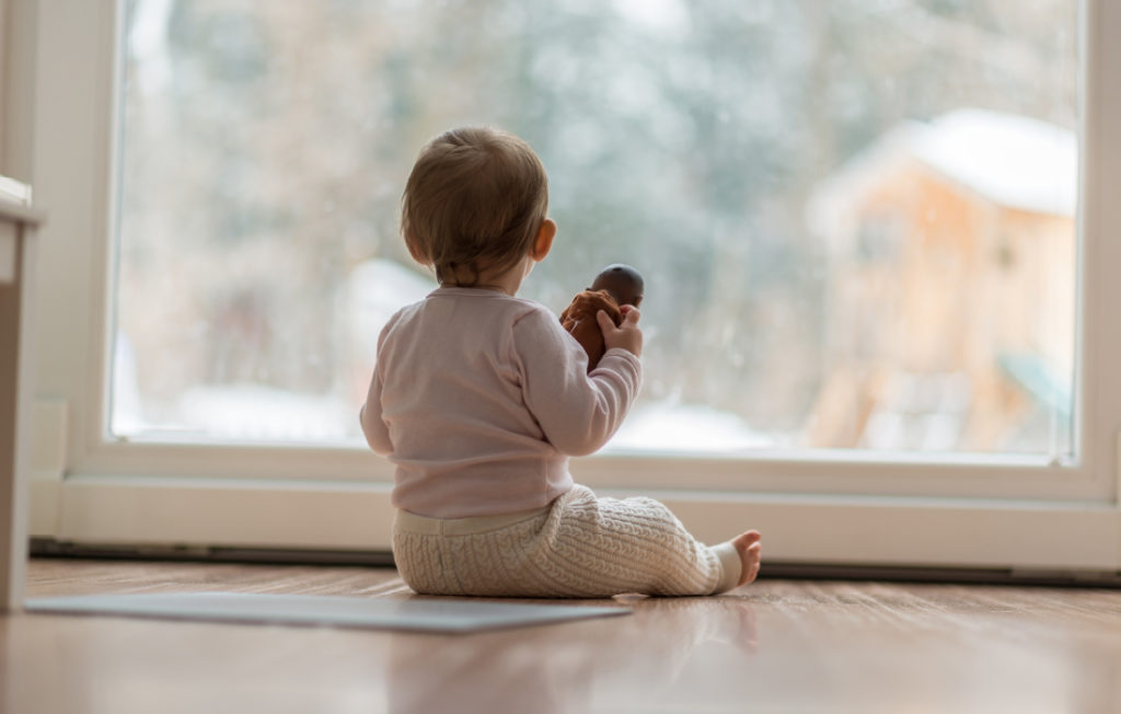 Bébé regarde par la fenêtre. Cette photo illustre l'article sur les émotions négatives des enfants.