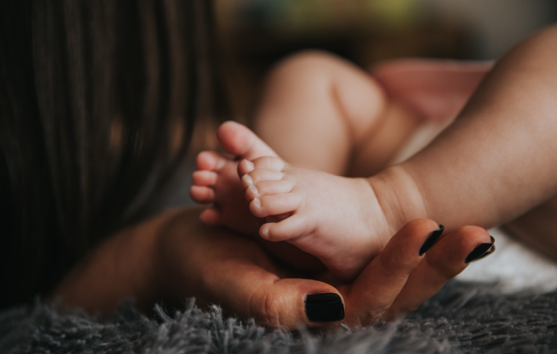 Une maman tient délicatement les pieds de son enfant. Cette photo illustre l'article sur l'anxiété chez l'enfant en temps de crise.