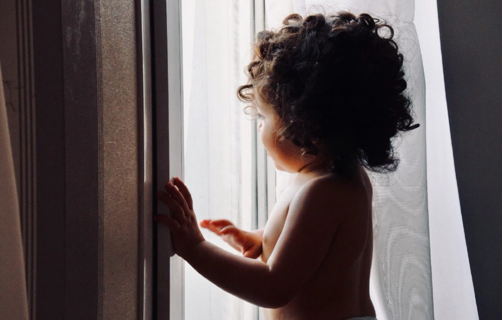 Enfant heureux qui regarde par la fenêtre.