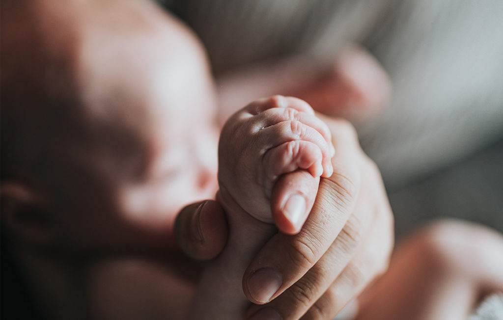 Une main d'enfant d'ans une main d'adulte. Photo illustrant un article sur l'intimité de l'enfant