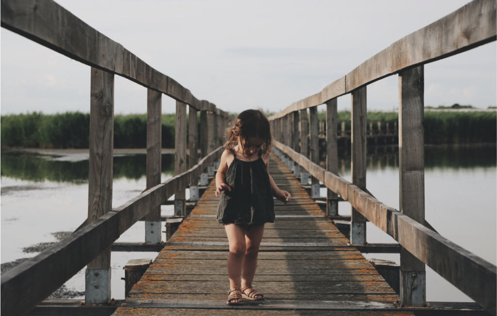 Petite fille sur un pont qui regarde ses pieds